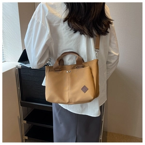 Rear view of khaki canvas tote bag with adjustable strap in a minimalist office setting