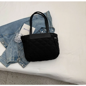 Detailed view of black quilted tote bag with rhombus stitching and leather handles