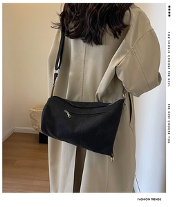 Detail view of the black canvas bag featuring a practical back zipper pocket and adjustable strap