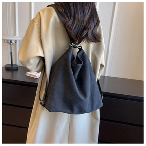 Macro detail of the durable black canvas backpack worn over a stylish trench coat