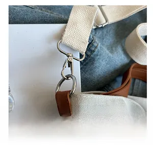 Detail of silver metal hook and leather connection on durable white canvas bag