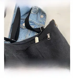 Detail view of the black canvas bag featuring a practical external silver zipper pocket
