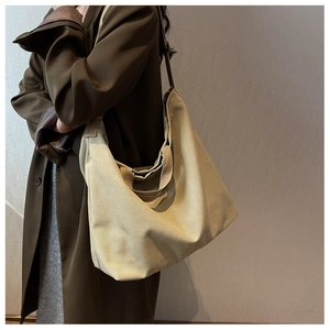 Grand sac bandoulière en toile kaki avec bandoulière et poignées sur manteau olive