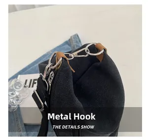 Detail show of silver metal hooks and brown leather trim on a black canvas bag