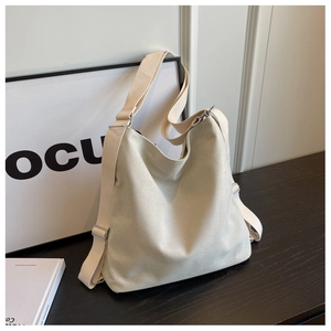 Detail of minimalist cream canvas tote showing wide fabric strap and adjustable metal buckle