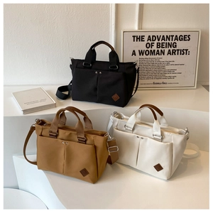 Three canvas tote bags in black, khaki, and beige colors with silver rivet details