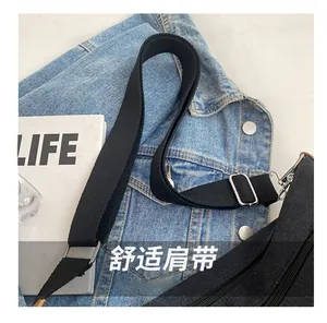 Detail of black canvas bag featuring adjustable fabric strap with silver metal buckle
