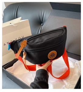 Detail of black canvas chest bag with orange strap and logo in premium gift box