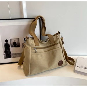 Détail du sac cabas en toile avec poche latérale, logo en cuir et bandoulière réglable