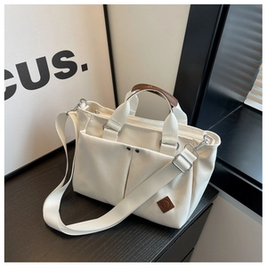 Close-up of cream canvas tote bag with brown leather handles and adjustable strap