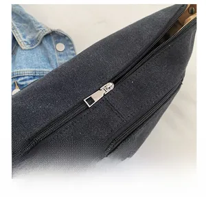 Detailed close-up of a smooth silver metal zipper on a durable black canvas shoulder bag