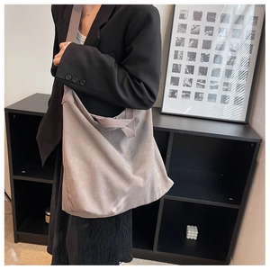 Sac bandoulière en toile grise porté par un mannequin dans un studio pour le trajet quotidien