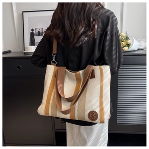 Detail of striped canvas tote bag showing the textured fabric and leather logo patch