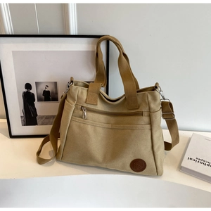 Détail du sac cabas en toile kaki avec poche zippée et logo rétro en cuir embossé