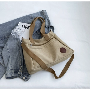Vue détaillée du sac cabas en toile kaki avec logo en cuir et poche zippée frontale