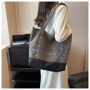 Detail of grey canvas tote bag with ethnic pattern embroidery and reinforced black base