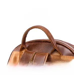 Detail of brown leather backpack featuring reinforced top handle and woven shoulder straps