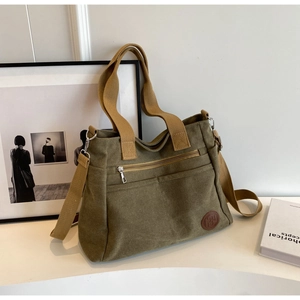 Détail du sac cabas en toile verte avec sangles brunes et poche zippée fonctionnelle