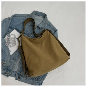Detail view of khaki large capacity canvas bag with metal buckle on denim fabric
