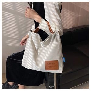 Lifestyle view of a person wearing a canvas tote bag with brown leather handles