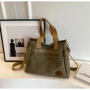 Détail du sac fourre-tout en toile olive avec poignées brunes et bandoulière réglable