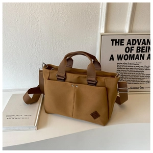 Detail showing khaki canvas tote with adjustable strap and decorative front pockets