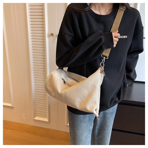 Detail view of cream canvas crossbody bag with sturdy silver metal hooks and zippers