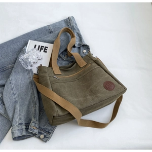Détail du sac fourre-tout en toile vert armée avec logo en cuir marron et poche zippée