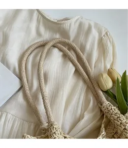 Close-up of beige woven tote bag with hollow mesh pattern and thick rope strap