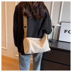 Detailed back view of a beige canvas crossbody bag with adjustable wide strap worn by model