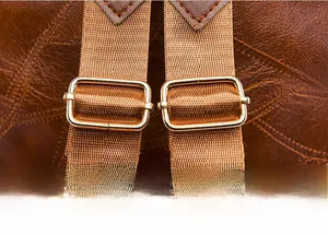 Detail of adjustable nylon straps and gold metal buckles on brown leather backpack