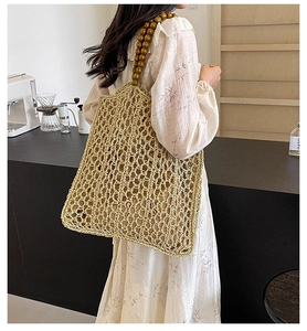 Detail of hand-woven beige straw tote bag with brown wooden bead handles for summer