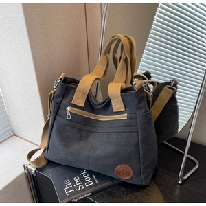 Gros plan d'un grand sac cabas en toile avec poche avant zippée et logo rond en cuir
