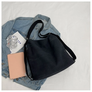 Detail of minimalist black canvas tote bag with adjustable strap and smooth matte finish