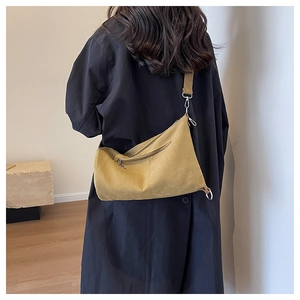 Rear view of model wearing a mustard yellow canvas crossbody bag with silver hardware
