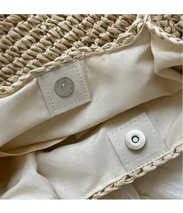Close-up of the woven straw texture and silver magnetic snap closure on the beach bag