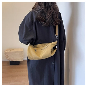 Detail shot of a yellow canvas crossbody bag featuring a fabric strap and metal buckle