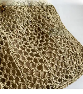 Detailed view of woven straw tote bag featuring hollow mesh craft and wood bead handles