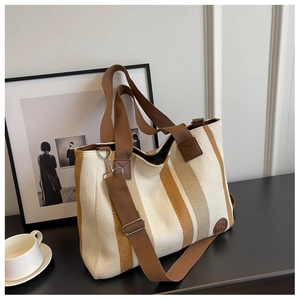 Detail of canvas tote bag with brown straps and striped pattern on office desk