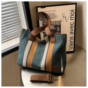 Detail of colorful striped canvas tote bag with brown handles and adjustable strap