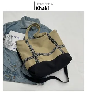 Detail of khaki and black canvas tote bag with embroidered ribbons and shoulder strap
