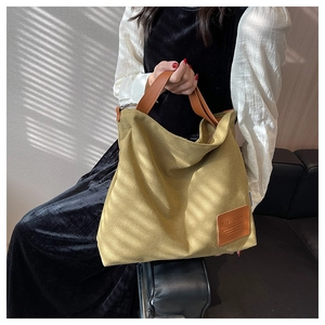 Detail of mustard yellow canvas tote with leather handle and fashion logo patch