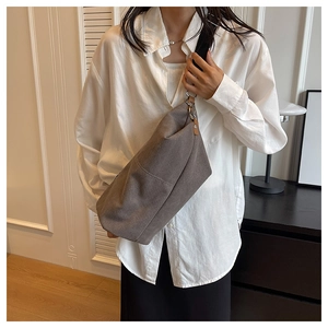 Detail of grey canvas crossbody bag with adjustable wide strap and leather trim accents