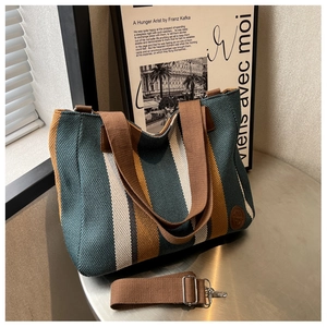 Detail of striped knitted tote bag with brown handles and adjustable crossbody strap