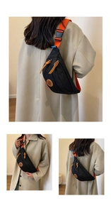 Detail of black nylon chest bag with orange strap, leather logo and buckle closure