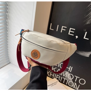 Detail of canvas chest bag featuring a round leather logo and durable zipper closure