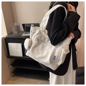 Detailed view of the large white Oxford tote bag with multiple pockets and a small round pouch