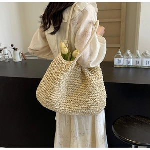 Detailed back view of a woman wearing the beige woven tote bag with tulip decorations