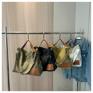 Detailed view of canvas tote bags in army green, black, yellow, and beige with leather straps