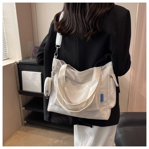 Close-up of white oxford tote bag with side pockets, webbing straps and hanging pouch